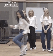 a group of girls are dancing in front of a whiteboard that says dream catcher on it