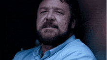 a man with a beard wearing a blue shirt looks at the camera