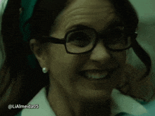 a woman wearing glasses and a green headband is smiling with the hashtag liaalmeida05