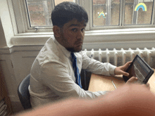a man sitting at a desk using a tablet computer