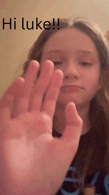 a girl says hi luke with her hand in front of her