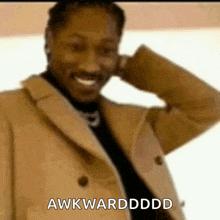 a man in a brown coat is smiling and says awkwarddddd
