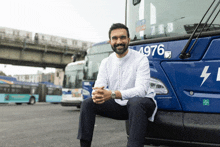 a man sits on the front of a bus with the number 4976 on the side