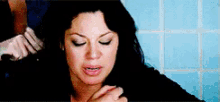 a woman is sitting in a bathroom with her eyes closed and a man is touching her hair .