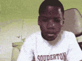 a young boy wearing a white shirt that says souderton on it