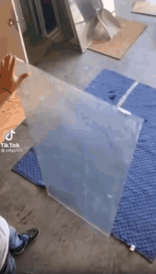 a person is holding a piece of clear plastic on top of a blue mat .