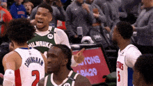 a basketball player wearing a milwaukee jersey talks to another player on the court