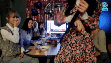 a group of women are sitting at a table with balloons and a sign that says 41 on it .