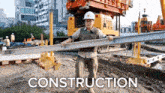 a construction site with a man carrying a beam