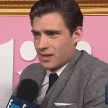 a man in a suit is talking into a microphone .