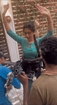 a woman is standing in front of a camera with her arms in the air while a man holds a camera .