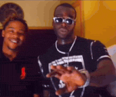 a man wearing sunglasses stands next to another man in a polo shirt