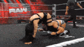 two women are wrestling in a ring with the word raw on the wall behind them