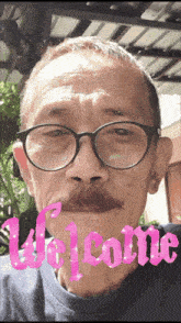 a man with glasses and a mustache says welcome in pink