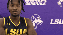 a man in a lsu jersey stands in front of a purple banner