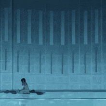 a woman sits on the floor in front of a wall with a row of lines on it