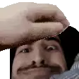 a close up of a man 's face with a hand on his forehead .