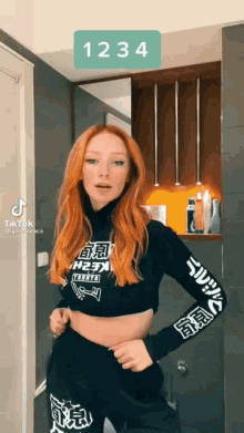 a woman with red hair is wearing a black crop top and black pants
