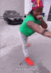 a girl in a green shirt and red shoes is standing on one leg with the words ain 't nuffin above her