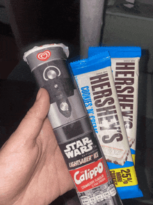 a person holding a star wars light saber ice bar next to a hershey bar