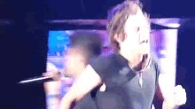 a man is singing into a microphone on a stage while dancing .