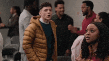 a group of people are standing in a room and one of them is wearing a yellow jacket .