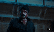 a man in a black shirt is holding a bloody knife in his hand .