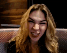 a woman is sitting in a chair making a funny face .