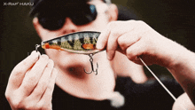 a man holding a fishing lure with x-rap haiku written in the corner