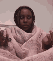 a woman is wrapped in a pink blanket and holding a pen
