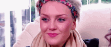 a woman wearing a headband and scarf is sitting on a couch .