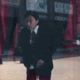 a man in a suit and tie is standing in front of a building with a sign that says ' ae ' on it