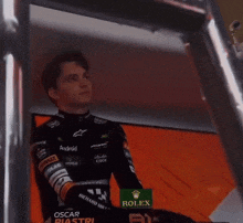 a man in a racing suit sits on a ladder in front of a screen that says 0:07
