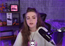 a woman sitting in front of a shure microphone in a room