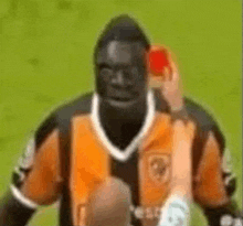 a soccer player is getting a red card while standing on the field .