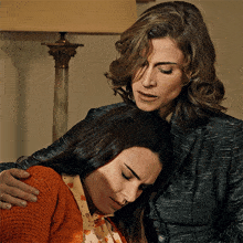 a woman is comforting another woman who is sitting down