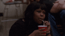 a woman is drinking through a straw from a red cup