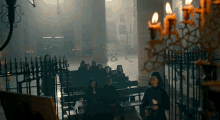 a group of people sitting in a church with candles lit