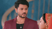 a man in a red suit and a woman in a red dress are standing next to each other and looking at each other .