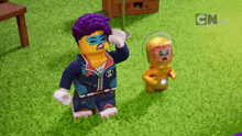 two lego characters standing next to each other on a grassy field with cn on the bottom right corner