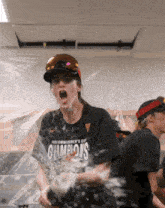 a woman wearing a shirt that says champions is being sprayed with water