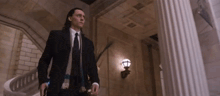 a man in a suit and tie is walking down stairs in a building