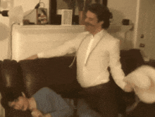 a man in a tuxedo is standing next to a couch