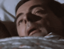 a close up of a man laying in bed with his eyes closed