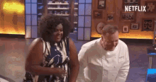 a man and a woman are standing next to each other in a kitchen with a netflix logo in the background .