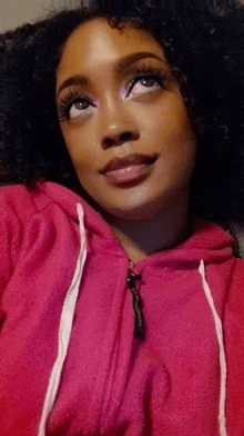 a woman wearing a pink hoodie is looking up at the camera .