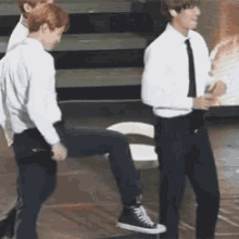 two men are standing next to each other on a stage and one of them is holding another man 's leg .