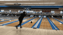 a woman throws a bowling ball in a bowling alley with a state farm sign in the background