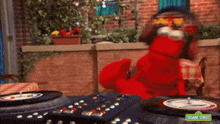 elmo from sesame street is sitting at a table with a record player .