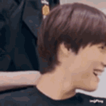 a close up of a man 's face with a blurred background . he is wearing a black shirt and smiling .